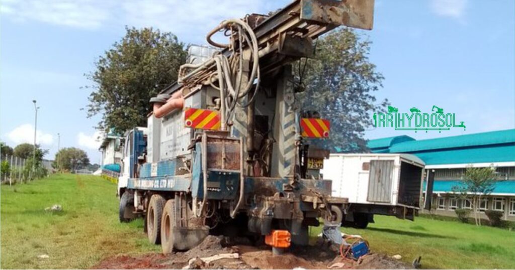 A fully operational borehole drilling rig alongside a support truck actively working on-site to access underground water.